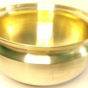 May include: A shiny, gold-colored bowl with a rounded body and a slightly flared rim. The bowl has a smooth, reflective surface, and the interior reflects the light. The bowl's design is simple and elegant, suitable for various uses.