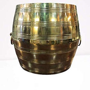 Könnte beinhalten: Ein großer, goldfarbener Metalltopf mit zwei Griffen. Der Topf hat eine abgerundete Form und ist mit horizontalen Linien verziert.