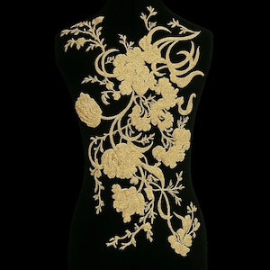 Könnte beinhalten: Eine schwarze Schneiderpuppe zeigt eine goldene Blumenstickerei. Die Stickerei zeigt detaillierte Blumen, Blätter und Ranken, die ein elegantes Muster bilden. Der goldene Faden bildet einen auffälligen Kontrast zum schwarzen Stoff.