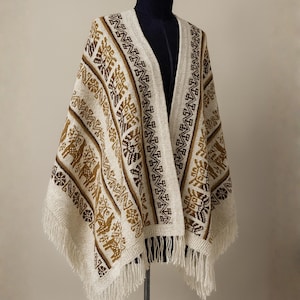 Puede incluir: Poncho color crema con patrones geométricos marrones y beige y flecos. El poncho se exhibe en un maniquí y presenta un diseño de cuello en V. El patrón incluye formas geométricas y animales estilizadas.