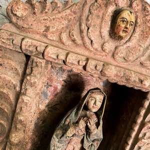 May include: A carved wooden niche with a painted figure of a woman in a robe. The niche has a decorative top with a carved face.