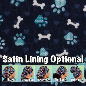 May include: A dark blue fabric with a pattern of white bones and blue paw prints. The fabric is for a surgical scrub hat. The image shows five different styles of scrub hats: Euro, Ponytail, Bouffant, Tie Back, and High Bun. The text "Satin Lining Optional" is displayed below the fabric.