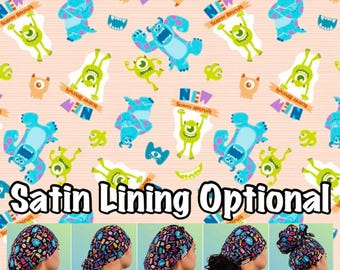 May include: A collection of scrub caps in five styles: Euro, Ponytail, Bouffant, Tie Back, and High Bun. The fabric features a light peach background with a repeating pattern of blue and green monsters and the text NEW Scorer Recruit.