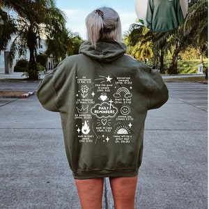 May include: A green hooded sweatshirt with white text that reads "Daily Reminders" and includes bible verses. The text is arranged in a circle with a cross in the center.