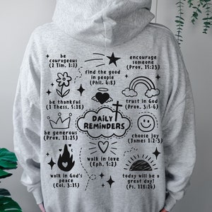 May include: Gray hoodie with black text and illustrations. The text includes bible verses and phrases like "Daily Reminders", "be courageous", "walk in love", and "trust in God".