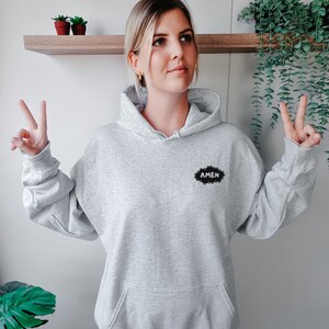 May include: A gray hooded sweatshirt with a black cloud-shaped patch that says "AMEN" in white lettering.