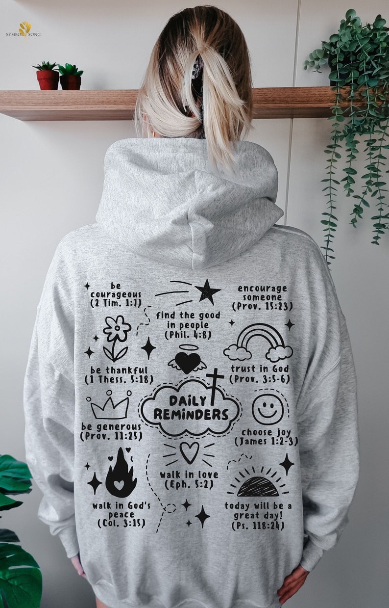 May include: Gray hoodie with black text and illustrations. The text includes bible verses and phrases like "Daily Reminders", "be courageous", "walk in love", and "trust in God".