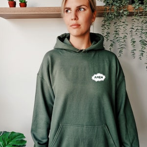 May include: A dark green hooded sweatshirt with a white cloud-shaped graphic that says "AMEN" in all caps.