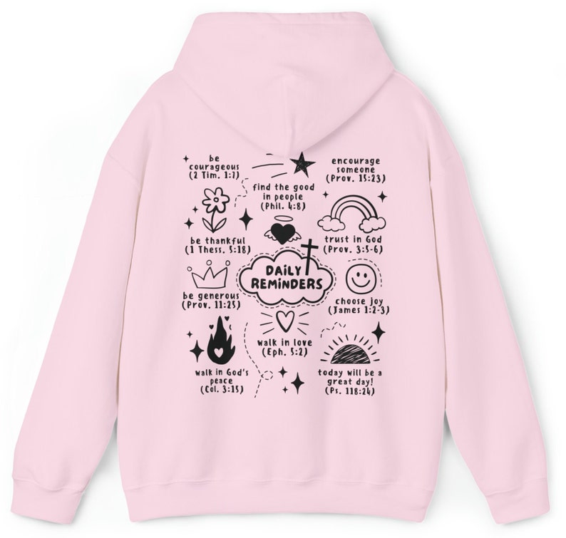 May include: Pink hoodie with a black print of daily reminders with bible verses and illustrations. The text includes: be courageous, be thankful, be generous, walk in God's peace, find the good in people, walk in love, encourage someone, trust in God, choose joy, today will be a great day!