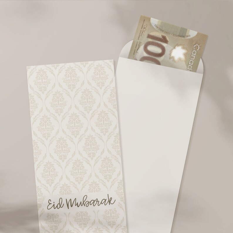 May include: A white envelope with a decorative pattern on the front. The envelope has a flap on the top and is open to reveal a Canadian $100 bill. The envelope has the text "Eid Mubarak" written on the front.