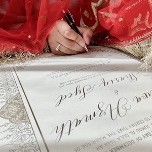 May include: A white wedding certificate with ornate borders. The document is signed with the names "Shariq Syed" and "wa Azmath" in elegant cursive script.