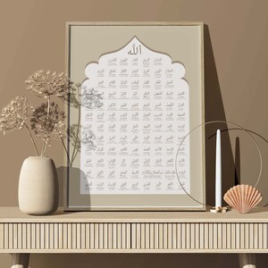 May include: A framed print with a beige background and a brown wooden frame. The print features a large arch with the Arabic word "Allah" at the top. Inside the arch are 99 names of Allah in Arabic script, each with a corresponding English translation.