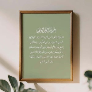 Op de afbeelding: Een ingelijst afdruk met een groene achtergrond en witte Arabische kalligrafie. De tekst luidt "Allah la ilaha illa huwa al-hay al-qayyum la ta'khudhuhu sinatun wa la nawm lahu ma fi al-samawati wa ma fi al-ard man dhalladhi yashafu 'indaka illa bi'idhnihi ya'lamu ma bayna aydihim wa ma khalfahum wa la yuhi'tun bi shay'in min 'ilmihi illa bima sha'a wa si'a kursiyuhu al-samawati wa al-ard wa la ya'uduhu hifdhuhuma wa huwa al-'aliyu al-'azim"