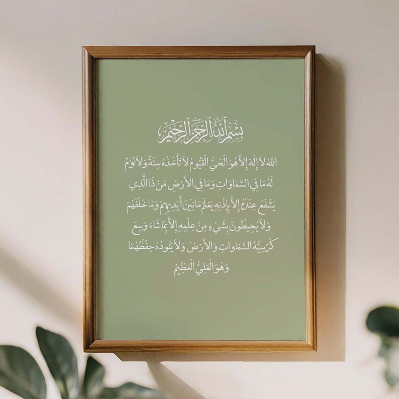 Op de afbeelding: Een ingelijst afdruk met een groene achtergrond en witte Arabische kalligrafie. De tekst luidt "Allah la ilaha illa huwa al-hay al-qayyum la ta'khudhuhu sinatun wa la nawm lahu ma fi al-samawati wa ma fi al-ard man dhalladhi yashafu 'indaka illa bi'idhnihi ya'lamu ma bayna aydihim wa ma khalfahum wa la yuhi'tun bi shay'in min 'ilmihi illa bima sha'a wa si'a kursiyuhu al-samawati wa al-ard wa la ya'uduhu hifdhuhuma wa huwa al-'aliyu al-'azim"