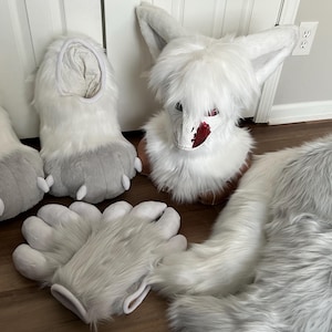 May include: A collection of white and gray furry fursuit parts, including feet paws, hand paws, a head, and a tail. The head has a detailed face with red accents. The paws and tail have gray accents.