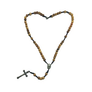 May include: A wooden rosary with brown beads and a silver crucifix. The rosary is arranged in the shape of a heart.