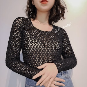 May include: A black crochet top with a loose, open-weave pattern. The top has long sleeves and a round neckline.