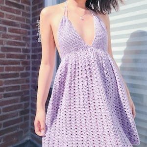 May include: A lavender crochet dress with a halter neckline and a flowing skirt. The dress is made with a delicate stitch pattern and has a relaxed fit.