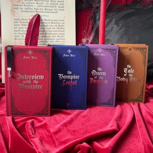 May include: Four hardcover books by Anne Rice, featuring the titles "Interview with the Vampire", "The Vampire Lestat", "The Queen of the Damned", and "The Tale of the Body Thief". The books are arranged in a row on a red velvet surface.