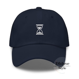 May include: Navy blue baseball cap with a white embroidered hourglass design on the front. The cap has a curved brim and a structured fit. The hat is a classic style, suitable for casual wear.