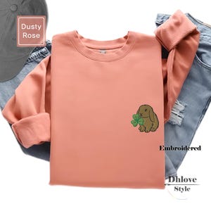 Könnte beinhalten: Ein Set aus drei Keramikbechern mit gesprenkelter, matter Oberfläche. Die Becher sind in den Farbtönen Creme, Hellgrau und Dunkelgrau gehalten. Jeder Becher hat ein schlichtes, minimalistisches Design und einen abgerundeten Henkel.