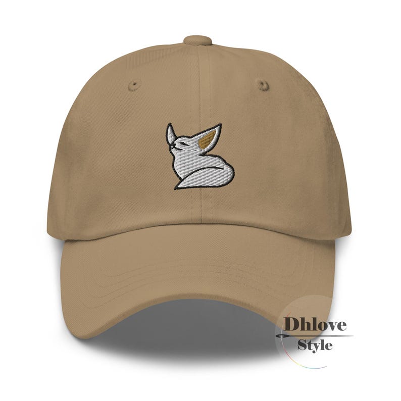 May include: A beige baseball cap with a curved peak. The cap has an embroidered design of a white and tan fox. The fox is in a relaxed pose with its eyes closed. The text "Dhlove Style" is printed on the lower right side of the cap.