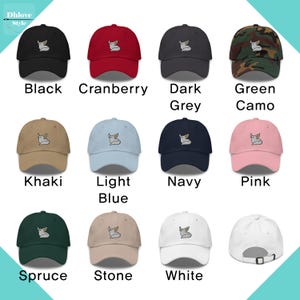 May include: A selection of baseball caps in colours such as black, cranberry, dark grey, and green camo. Each cap has an embroidered design and is labelled with its colour. The caps are arranged in rows and columns, displaying the range of options available.