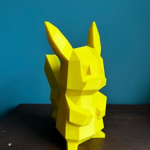 May include: A bright yellow, low-poly 3D printed figurine of a Pikachu, a popular character from the Pokemon franchise.