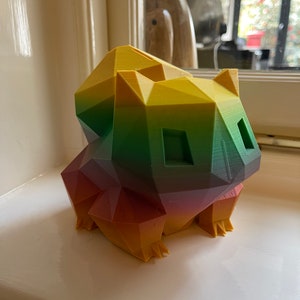 Peut inclure: Une figurine g&eacute;om&eacute;trique d'un animal de dessin anim&eacute; imprim&eacute;e en 3D avec un d&eacute;grad&eacute; de couleurs arc-en-ciel. La figurine est en plastique et pr&eacute;sente un d&eacute;grad&eacute; de couleurs jaune, vert, rouge et orange.