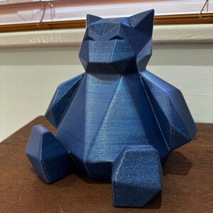 May include: A blue geometric bear figurine with a textured finish. The bear is sitting with its legs crossed and has a simple, modern design.
