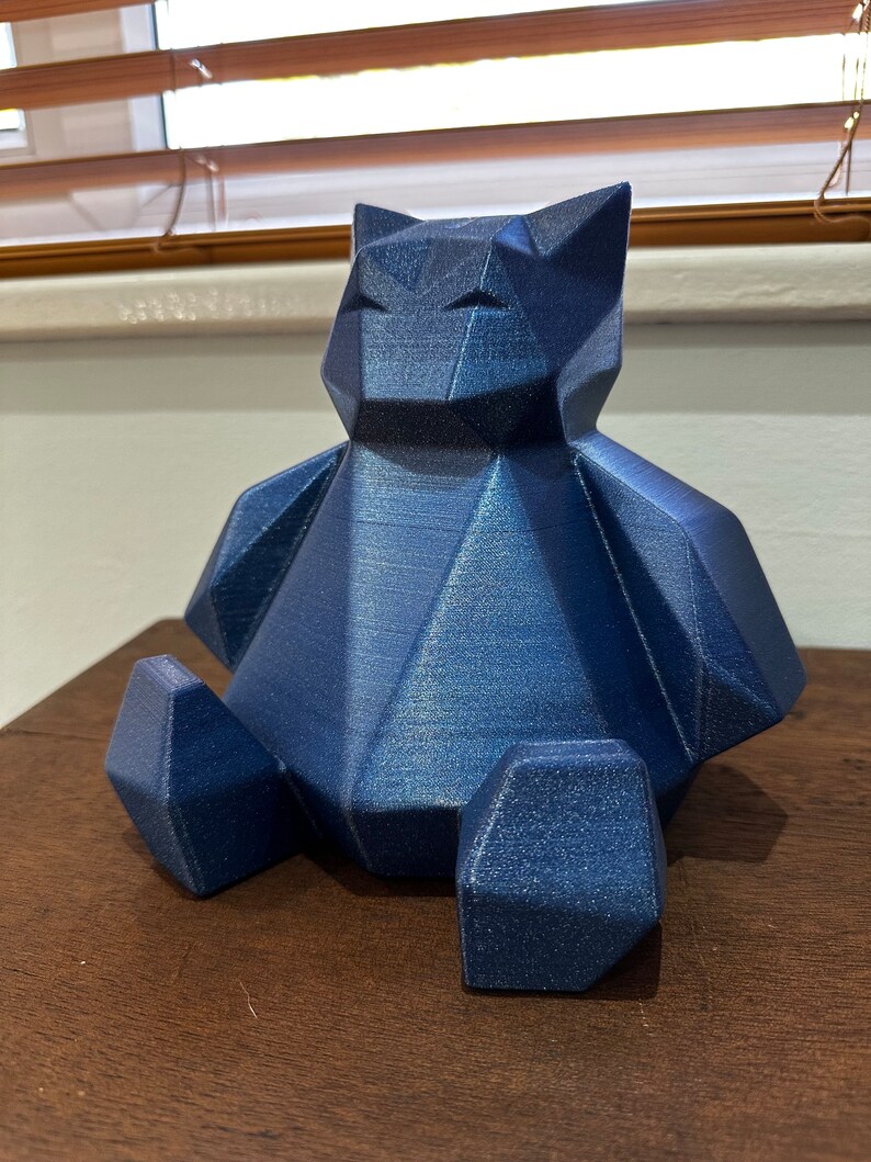 May include: A blue geometric bear figurine with a textured finish. The bear is sitting with its legs crossed and has a simple, modern design.