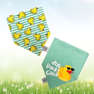 May include: Two fabric bandanas, one with a green background and the text "Zero Ducks Given" and a cartoon rubber duck wearing sunglasses, and the other with a white background and a repeating pattern of yellow rubber ducks on a green and white striped background.