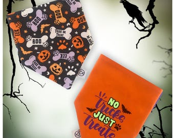 Puede incluir: Dos bandanas para perros de Halloween. Una es negra con calabazas naranjas y moradas, huesos, murciélagos y las palabras "Trick or Treat" y "Boo". La otra es naranja con texto morado que dice "No Tricks Just Treats" y una huella de pata.