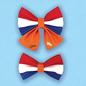 May include: Two bow ties in the colors of the Dutch flag: red, white, and blue. The larger bow tie has a gold crown on each side. The smaller bow tie is plain.