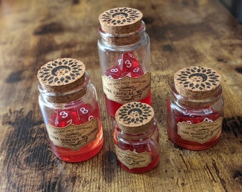 Puede incluir: Cuatro botellas de vidrio llenas de líquido rojo y un dado rojo de 20 caras. Cada botella tiene un tapón de corcho con un diseño negro y una etiqueta que dice "Poción de" y "Curar" seguido de un tipo de herida.
