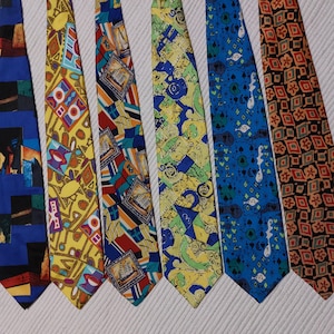 以下が含まれることがあります： さまざまなカラフルな模様のネクタイ7本のコレクション。ネクタイは、青、黄、赤、緑の色合いで、幾何学的な形、抽象的なデザイン、繰り返しのモチーフを表示しています。各ネクタイは滑らかな生地で作られています。