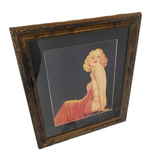 May include: Framed vintage art print featuring a seated woman with blonde hair, draped in a red shawl. The artwork is set against a dark background and framed in a decorative gold-toned frame, showcasing a classic aesthetic.