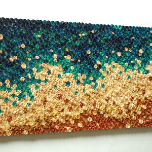 Può includere: Un'opera d'arte murale realizzata con cerchi di carta arrotolati in tonalità di blu, verde, giallo e arancio. I cerchi sono disposti in un motivo ondulato, creando un design testurizzato e astratto.