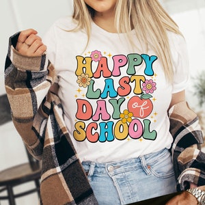 May include: White t-shirt with a colorful retro graphic that says "Happy Last Day of School" with flowers and an apple.