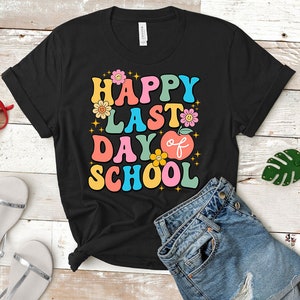 May include: Black t-shirt with a colorful retro graphic that says "Happy Last Day of School" with flowers and an apple.