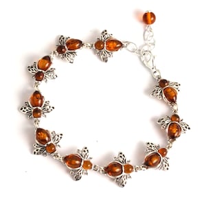 May include: A silver bracelet with amber bee charms. The bracelet has a lobster clasp closure.