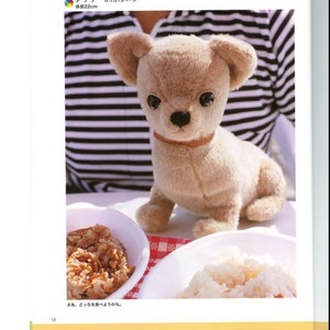 May include: A beige plush chihuahua toy with brown eyes and a brown collar. The toy is sitting on a white surface with two bowls of food in the background. The text "さあ、どっちを食べようかな。" is written in Japanese below the toy.