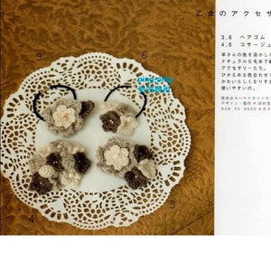 May include: Four crocheted hair scrunchies with brown and white yarn. The scrunchies are arranged on a white doily.