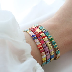May include: A stack of colorful bracelets with gold accents. The bracelets are made of small, square tiles in various colors, including red, pink, blue, turquoise, and yellow.