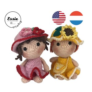 Puede incluir: Dos muñecas de crochet que llevan sombreros y vestidos. La muñeca de la izquierda lleva un vestido rosa con ribete rojo y un sombrero rojo con flores rosas. La muñeca de la derecha lleva un vestido amarillo con un sombrero amarillo y un girasol en la parte superior.