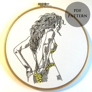 May include: Embroidered hoop art featuring a line drawing of a person in a yellow and black polka dot bikini. The person is facing away from the viewer and is adjusting their bikini bottom.