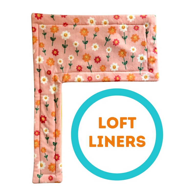 May include: Pink fabric item with a repeating pattern of smiling flowers in orange, white, and red. The item is rectangular with an L-shaped extension. The text "LOFT LINERS" is in a blue circle.