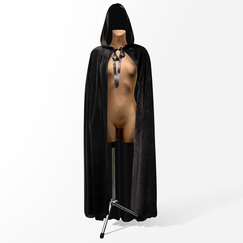 May include: A black velvet hooded cape with a black ribbon tie. The cape is draped over a mannequin.