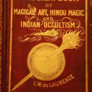 Może przedstawiać: Okładka czerwonej książki zatytułowanej "The Great Book of Magical Art, Hindu Magic and Indian Occultism" ze złotymi literami. Książka zawiera złotą pieczęć z napisem "Hindu Seals Amulets Charms Exorcisms Enchantments Benedictions" i złoty wz&oacute;r pi&oacute;ra.