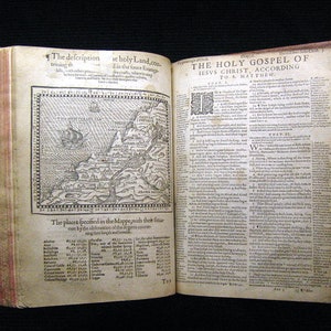 May include: An antique book with a map of the Holy Land and text from the Holy Gospel of Jesus Christ according to St. Matthew. The book has a brown leather cover and is open to a page with a map and a list of places.